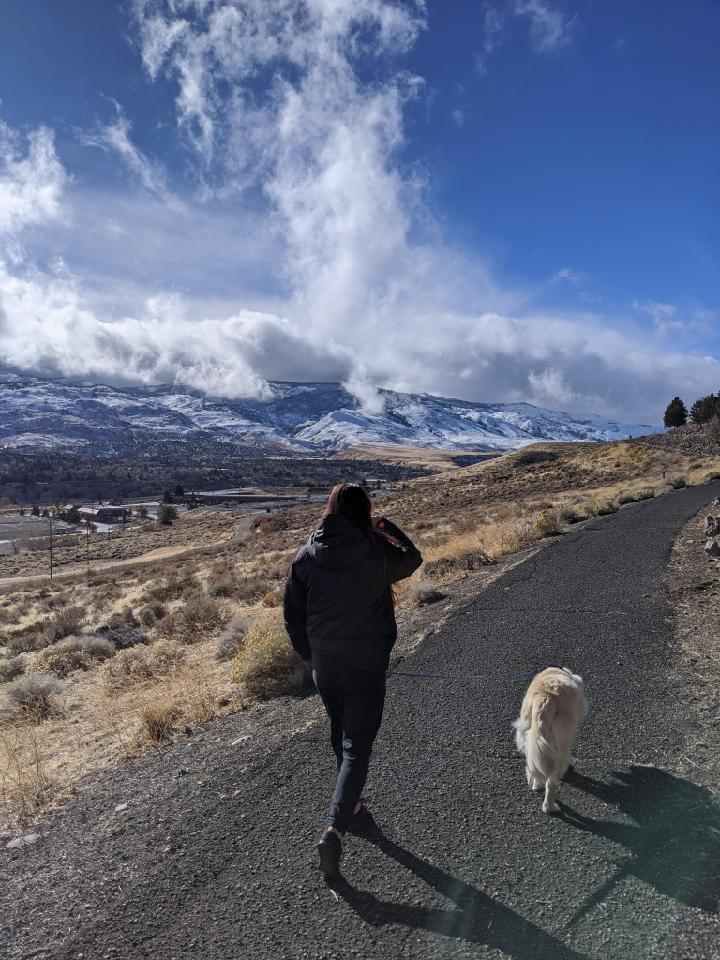 woman walking dog with mountains in background